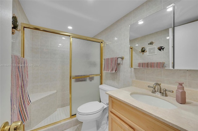 bathroom featuring vanity, a shower with door, tile patterned flooring, toilet, and tile walls