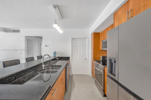 kitchen featuring light tile patterned flooring, stainless steel appliances, pendant lighting, sink, and dark stone countertops