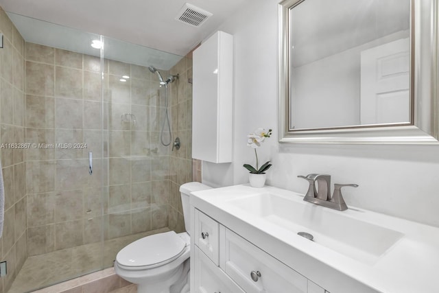 bathroom featuring vanity, a tile shower, and toilet