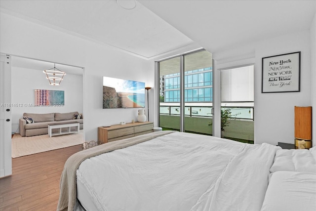 bedroom with wood-type flooring, floor to ceiling windows, and access to exterior