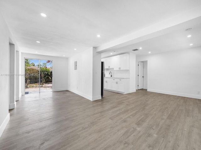 unfurnished living room featuring sink and light wood-type flooring