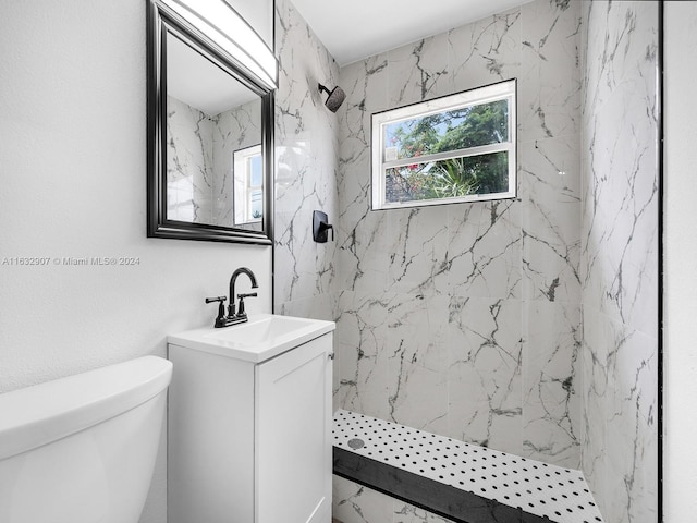 bathroom with vanity, a tile shower, and toilet