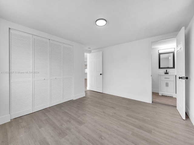 unfurnished bedroom featuring light hardwood / wood-style floors, sink, and a closet