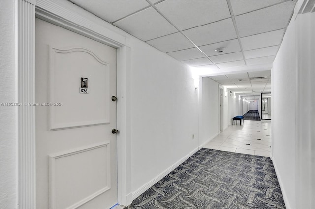 hallway featuring a paneled ceiling and tile patterned flooring