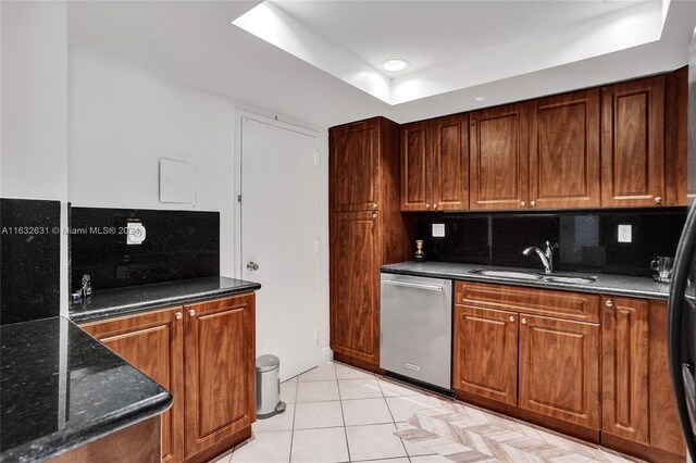 kitchen with tasteful backsplash, sink, dark stone countertops, dishwasher, and light tile patterned floors