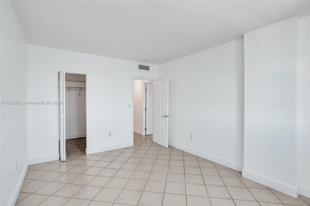 unfurnished bedroom with a closet, light tile patterned floors, and a walk in closet