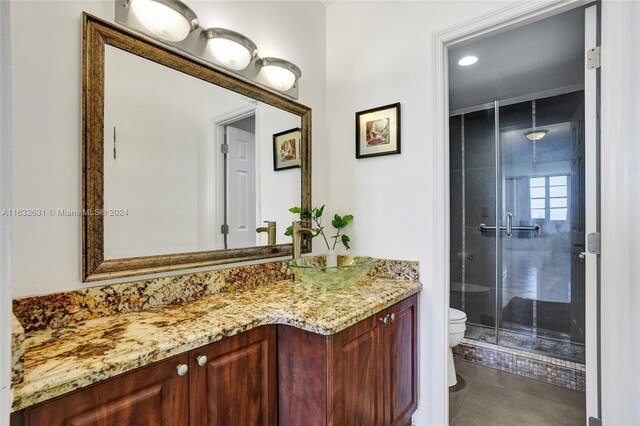 bathroom featuring a shower with shower door, vanity, tile patterned floors, and toilet