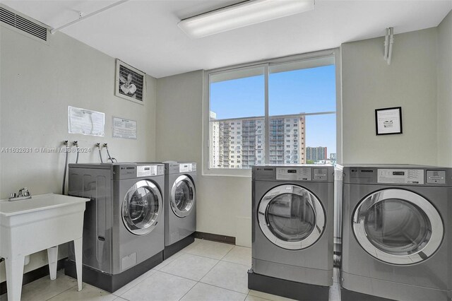 laundry area with washer and clothes dryer and light tile patterned floors