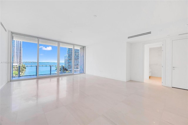 unfurnished room featuring a water view, light tile patterned floors, and floor to ceiling windows