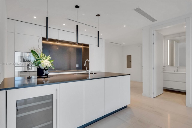 kitchen with light tile patterned flooring, beverage cooler, white cabinets, and decorative light fixtures