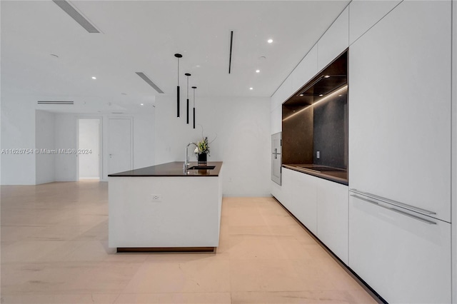 kitchen with white cabinetry, light tile patterned floors, sink, pendant lighting, and a center island with sink