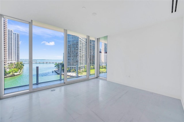 spare room with a water view, tile patterned flooring, and floor to ceiling windows