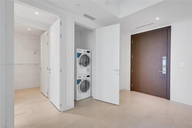 clothes washing area featuring light tile patterned flooring and stacked washer and dryer