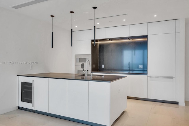 kitchen featuring white cabinetry, light tile patterned floors, beverage cooler, decorative light fixtures, and sink