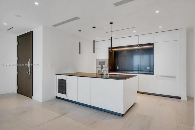 kitchen with white cabinetry, beverage cooler, pendant lighting, and an island with sink