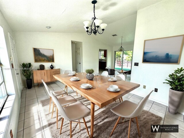 dining area featuring a chandelier, vaulted ceiling, and light tile patterned floors