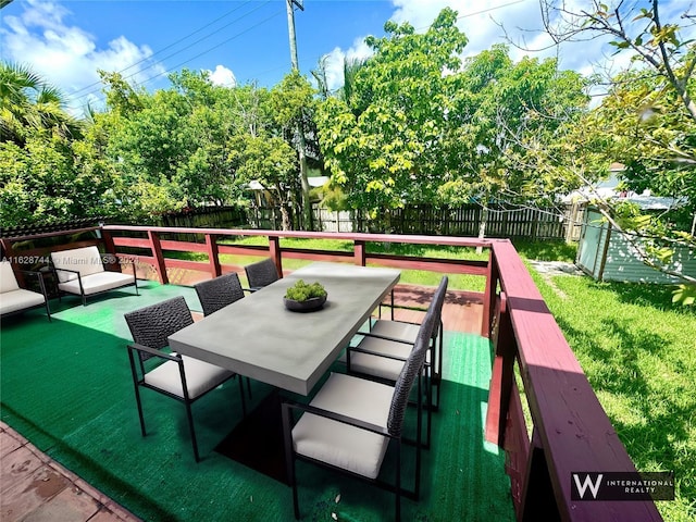 view of home's community featuring a deck, outdoor dining area, a fenced backyard, and a lawn