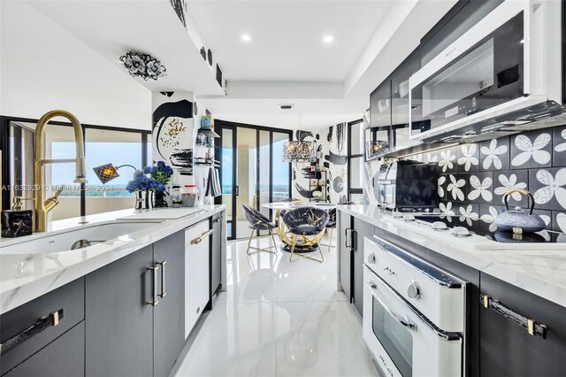 kitchen featuring light tile patterned floors, decorative backsplash, oven, and a tray ceiling