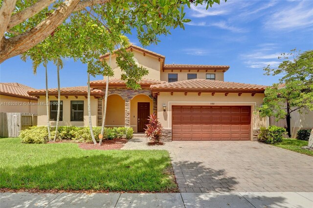 mediterranean / spanish home featuring a garage and a front lawn