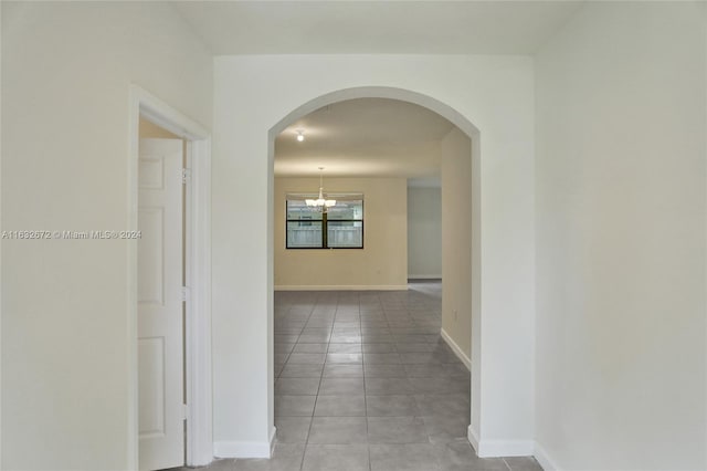 hall with light tile patterned flooring and an inviting chandelier