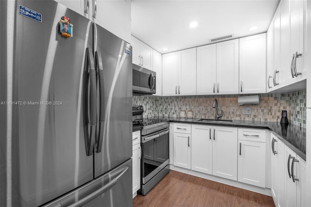 kitchen with stainless steel appliances, white cabinets, sink, backsplash, and dark wood-type flooring