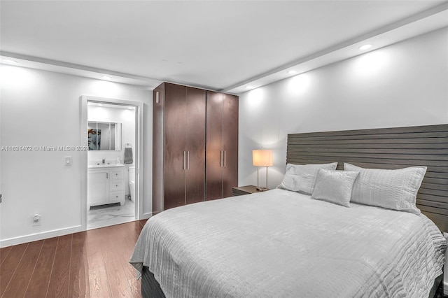 bedroom featuring a closet, connected bathroom, and hardwood / wood-style floors