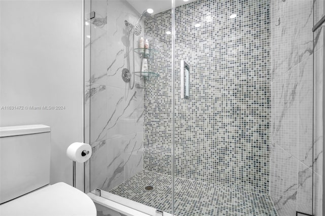 bathroom with a shower with door and toilet