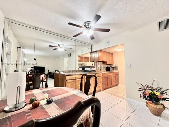 dining space with ceiling fan, a textured ceiling, and light tile patterned floors