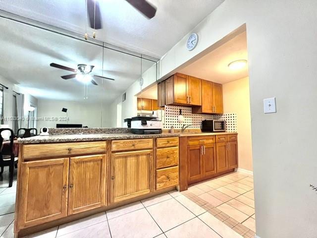 kitchen featuring ceiling fan, kitchen peninsula, and light tile patterned floors