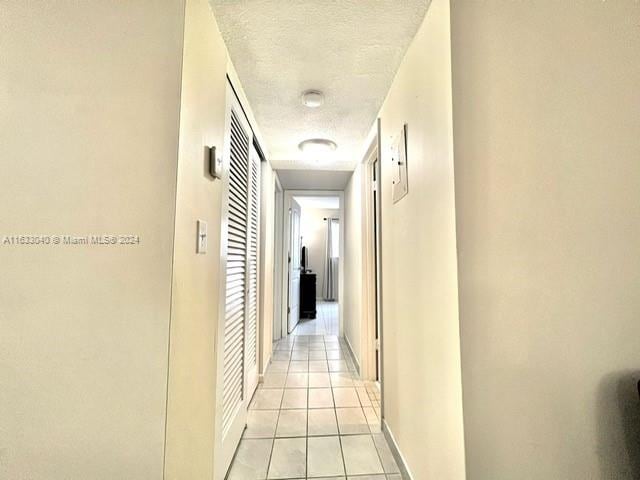 corridor featuring a textured ceiling and light tile patterned floors