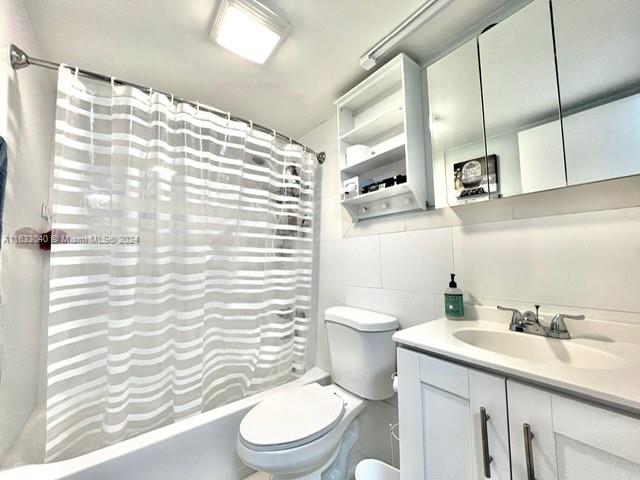 full bathroom with vanity, tile walls, toilet, and shower / bath combo