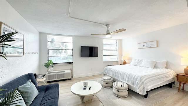 bedroom featuring a textured ceiling, ceiling fan, baseboards, and light wood-style floors