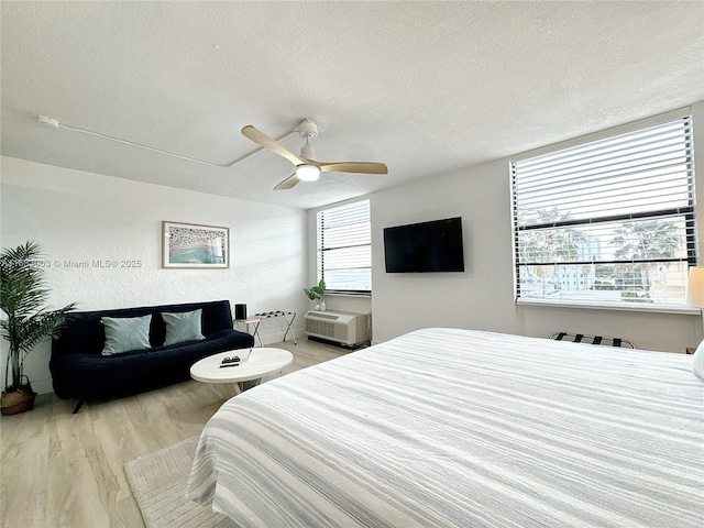 bedroom featuring light wood-style floors, ceiling fan, and a textured ceiling