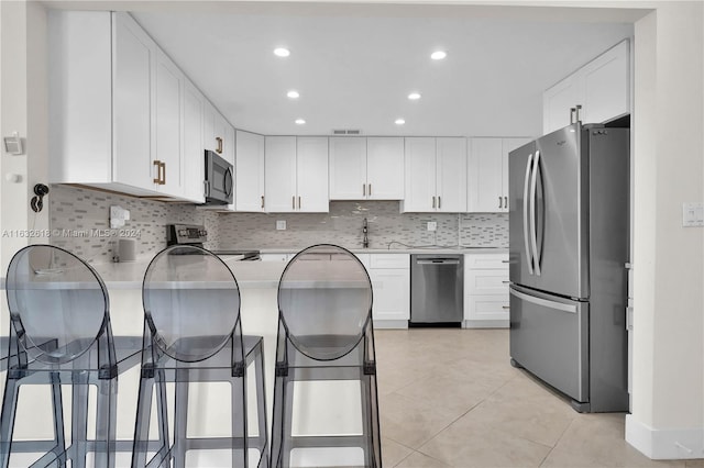 kitchen featuring decorative backsplash, white cabinetry, and stainless steel appliances