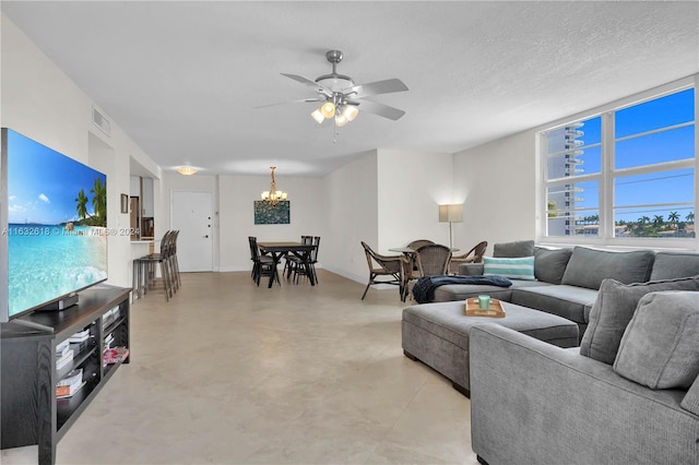 living room featuring ceiling fan with notable chandelier and a textured ceiling