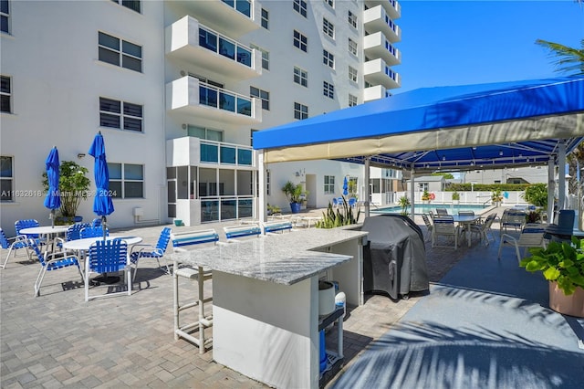 view of patio featuring area for grilling, an outdoor bar, and a community pool