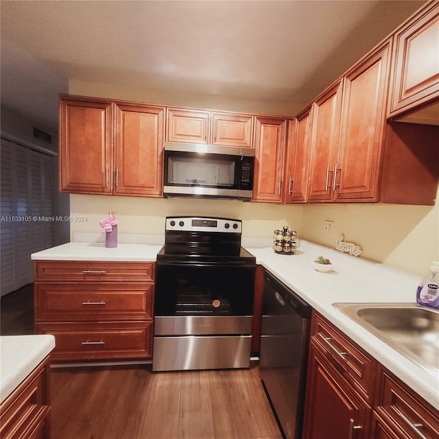 kitchen with dark wood-style floors, light countertops, appliances with stainless steel finishes, and a sink