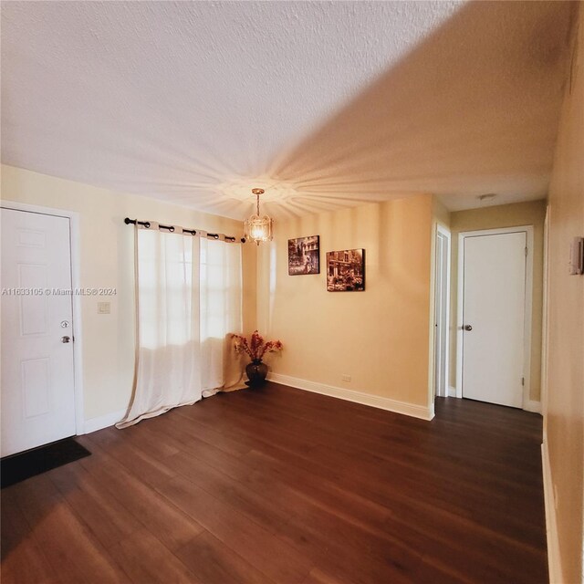 spare room featuring a textured ceiling and dark hardwood / wood-style flooring