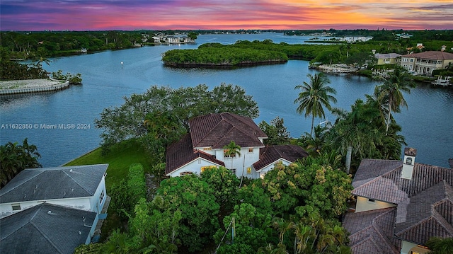 aerial view at dusk featuring a water view