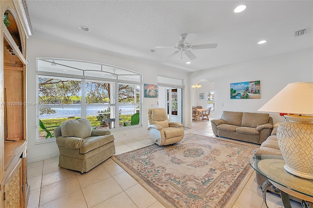 living room featuring a textured ceiling, ceiling fan, and light tile patterned floors