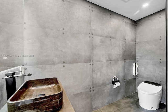 bathroom with toilet, tile patterned floors, and tile walls