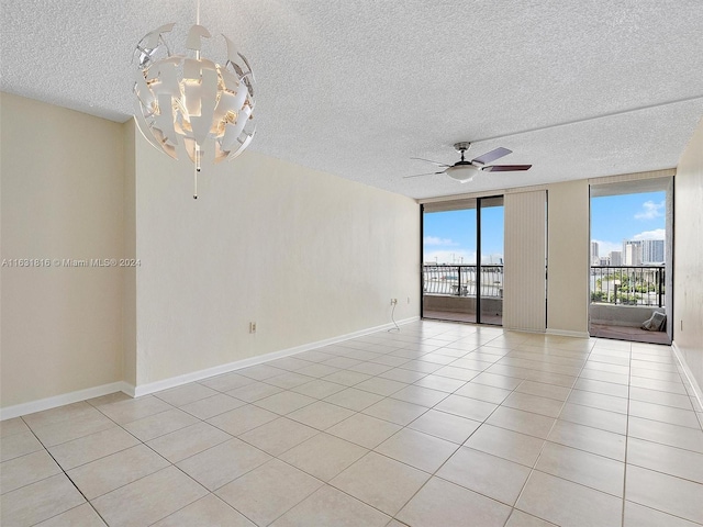 tiled spare room with floor to ceiling windows, ceiling fan with notable chandelier, and a textured ceiling