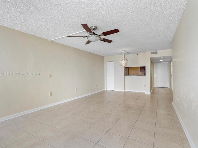 empty room featuring light tile patterned floors, a textured ceiling, and ceiling fan