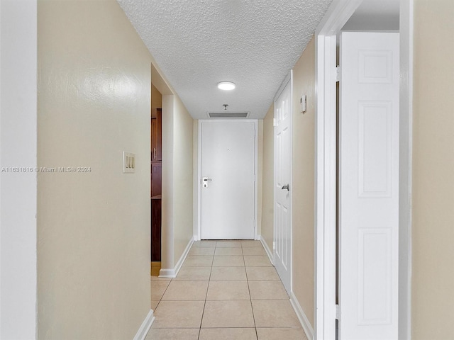 hallway with light tile patterned floors and a textured ceiling