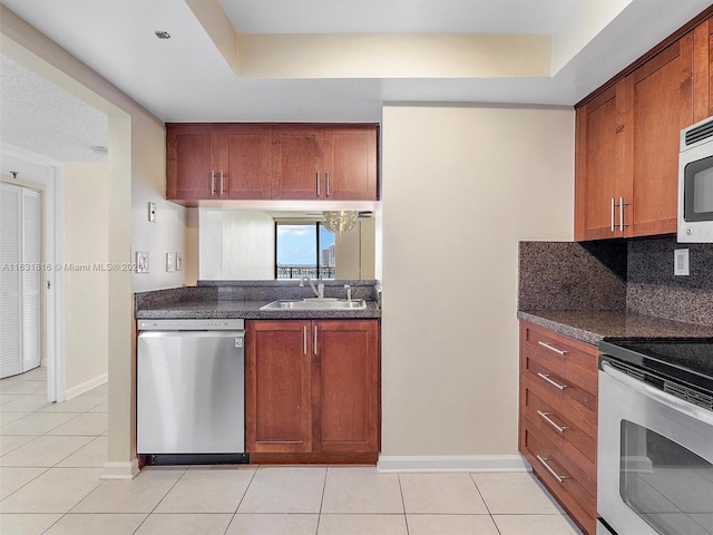 kitchen featuring light tile patterned flooring, sink, a raised ceiling, stainless steel appliances, and decorative backsplash