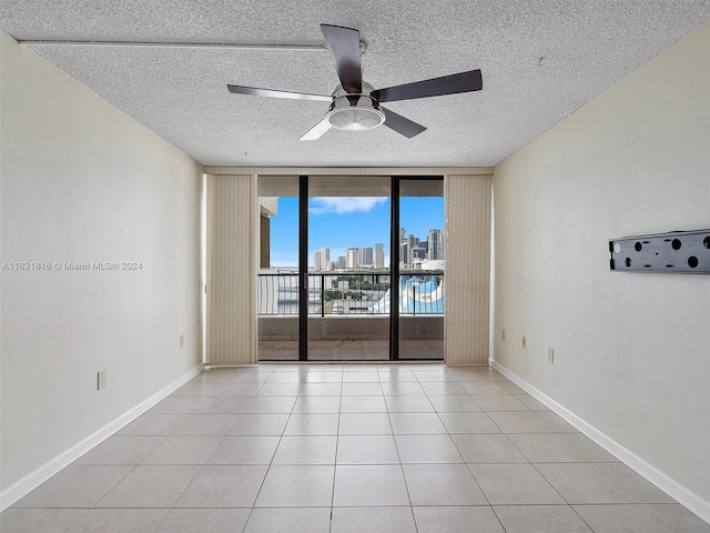 tiled spare room featuring expansive windows, ceiling fan, and a textured ceiling