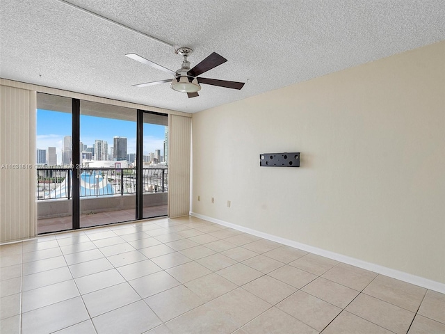 tiled spare room featuring expansive windows, ceiling fan, and a textured ceiling