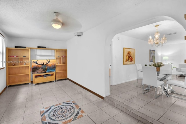 interior space with ceiling fan with notable chandelier, light tile patterned floors, and a textured ceiling