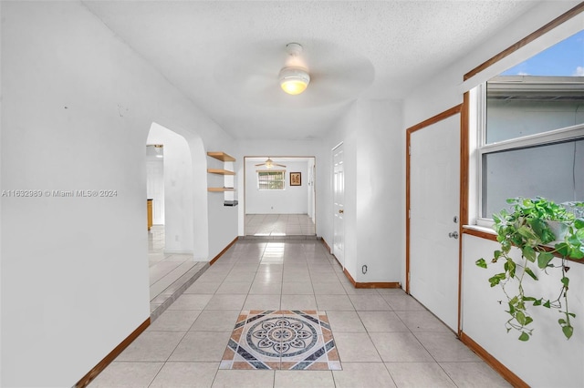 hall featuring light tile patterned flooring and a textured ceiling