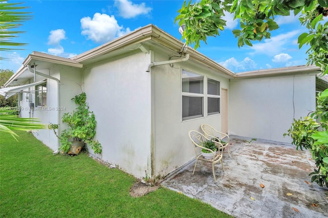 view of side of home with a patio area and a yard